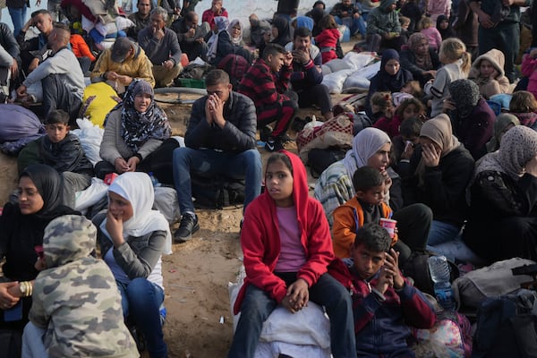 Palestinians wait next to their belongings in central Gaza, Saturday, Jan. 25, 2025, as the Israeli military is warning Palestinians not to return to northern Gaza. (AP Photo/Abdel Kareem Hana)