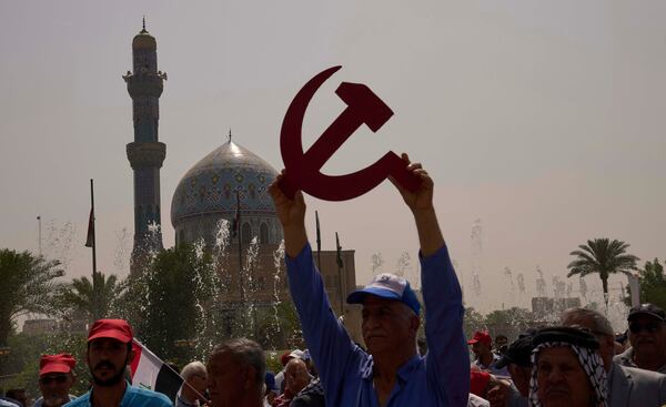 A supporter of the Iraqi Communist Party waves with a symbolic hammer and sickle and the communist flags as they take part in the May Day celebration in Baghdad, Iraq, Thursday, May 1, 2025. (AP Photo/Hadi Mizban)