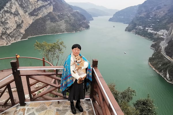 In this photo released by Tan Yuanyi, Zhang Yali poses for photos Dec 8, 2023, with her dog "Little Cotton" near a mountain pass that went viral in China in 2025 as "puppy mountain" in Yichang, a city in central China's Hubei Province. (Tan Yuanyi via AP)