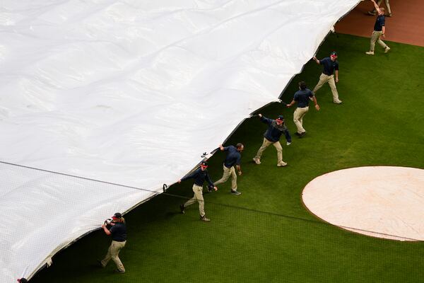 Crews cover the field before a rain-delayed baseball game between the Atlanta Braves and the Los Angeles Dodgers, Saturday, May 3, 2025, in Atlanta. (AP Photo/Mike Stewart)