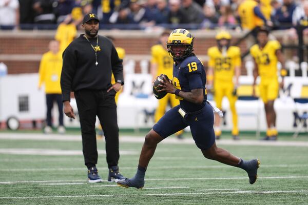 Michigan quarterback Bryce Underwood (19) rolls out to throw as head coach Sherrone Moore watches during an NCAA college football spring game in Ann Arbor, Mich., Saturday, April 19, 2025. (AP Photo/Paul Sancya)