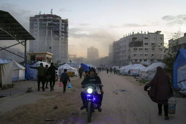 Palestinians walk and drive past tents shortly after an Israeli army airstrike nearby, in central Gaza City, Saturday, March 22, 2025. (AP Photo/Jehad Alshrafi)