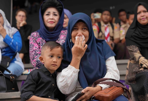 Muslina, a 43-year-old civil servant who is also a tsunami survivor weeps as she and her son Zayyan Firdaus Akmal watch a stage performance depicting the Indian Ocean tsunami in 2004, in Banda Aceh, Indonesia, Saturday, Dec 14, 2024. (AP Photo/Achmad Ibrahim)