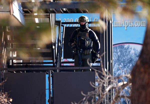 A law enforcement officer stands on a set of stairs outside an apartment complex during a raid Wednesday, Feb. 5, 2025, in east Denver. (AP Photo/David Zalubowski)