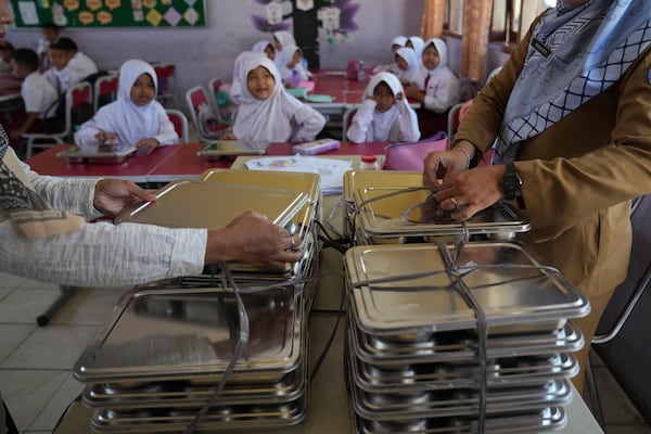 Teachers prepare meals for students during the kick off of President Prabowo Subianto's ambitious free meal program to feed children and pregnant women nationwide despite critics saying that its required logistics could hurt Indonesia's state finances and economy, at an elementary school in Depok, West Java, Indonesia, Monday, Jan. 6, 2025. (AP Photo/Dita Alangkara)