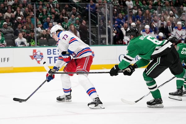 New York Rangers center Matt Rempe (73) controls the puck on an attack as Dallas Stars' Lian Bichsel, front right, attempts to break up the play in the second period of an NHL hockey game in Dallas, Friday, Dec. 20, 2024. (AP Photo/Tony Gutierrez)