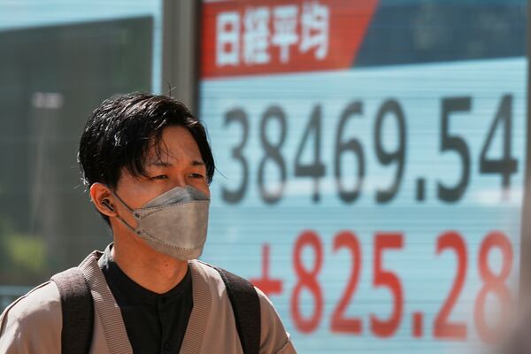 A person walks in front of an electronic stock board showing Japan's Nikkei index at a securities firm Tuesday, May 13, 2025, in Tokyo. (AP Photo/Eugene Hoshiko)