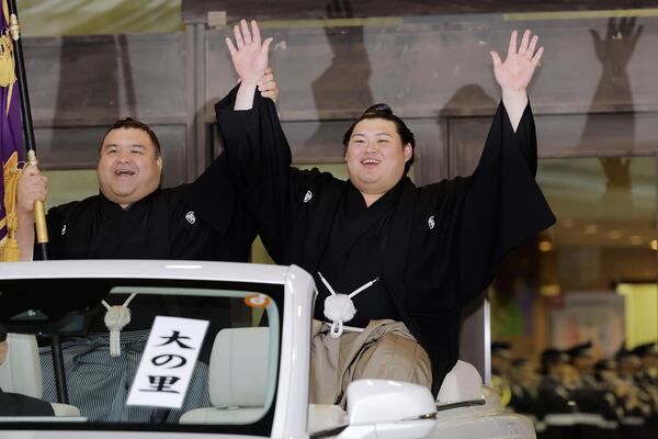 Onosato, right, raises hands for his victory of a sumo wrestling tournament during a celebratory parade at Ryogoku Kokugikan arena in Tokyo, Sunday, May 25, 2025. (Daiki Katagiri/Kyodo News via AP)