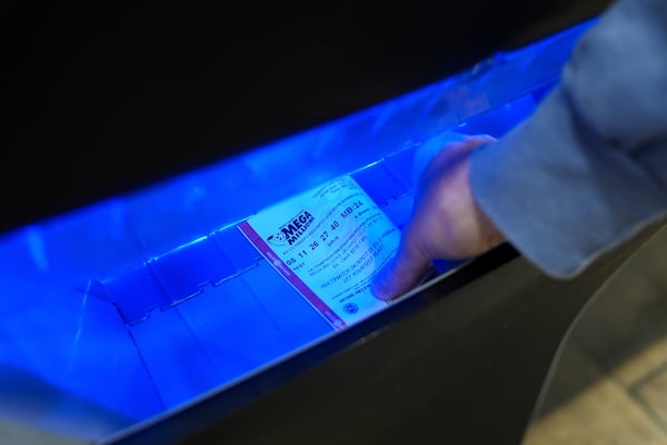 A person retrieves a Mega Millions lottery ticket from a self-serve terminal ahead of Friday's Mega Millions drawing of $1.15 billion, Thursday, Dec. 26, 2024, in Baltimore. (AP Photo/Stephanie Scarbrough)