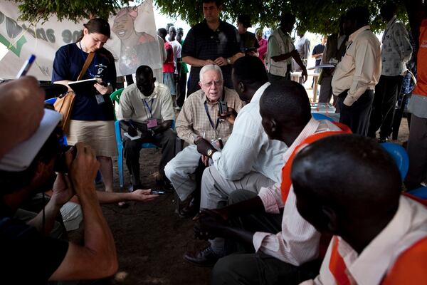 FILE - Former U.S. President Jimmy Carter, center, speaks with journalists and voting station authorities outside a polling station near Juba, southern Sudan, April 13, 2010. (AP Photo/Pete Muller, File)