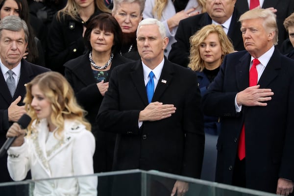 FILE - Vice President Mike Pence, center, and President Donald Trump, right, listen to the singing of the national anthem by Jackie Evancho during the 58th Presidential Inauguration at the U.S. Capitol in Washington, Jan. 20, 2017. (AP Photo/Andrew Harnik, File)