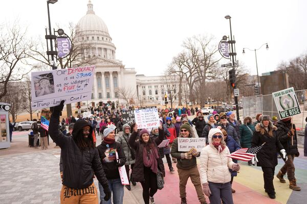 People hold up signs during a protest outside the Wisconsin Capitol Wednesday, Feb. 5, 2025, in Madison, Wis. (AP Photo/Morry Gash)