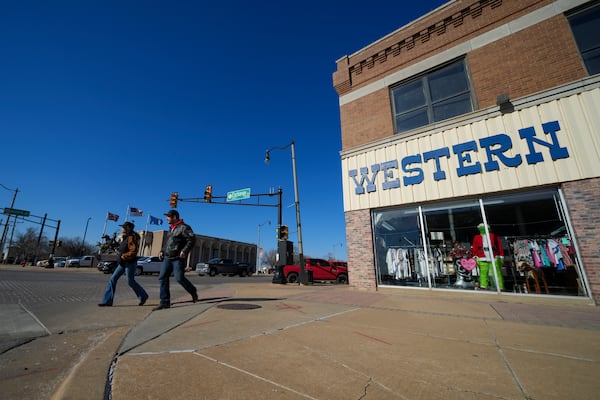 Canada tourists Kim Desilets, left, and Matthew Gagnon cross the street at Stockyards City near a Western-themed store after attending a cattle auction at the Oklahoma National Stockyards Tuesday, Jan. 14, 2025, in Oklahoma City. (AP Photo/Julio Cortez)