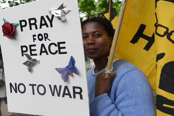 Casey Oware, a member of the Princeton Friends Meeting, holds a banner after meeting members of the Quaker March to Washington in Princeton, N.J., on Wednesday May 7, 2025. (AP Photo/Luis Andres Henao)