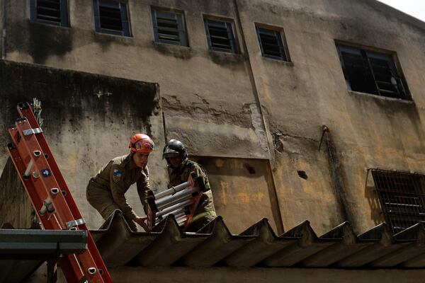 Firefighters move a ladder after a fire destroyed a factory that produces Carnival costumes for the lower division samba schools in Rio de Janeiro, Wednesday, Feb. 12, 2025. (AP Photo/Bruna Prado)