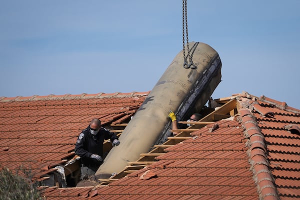 Israeli bomb squad police officers remove part of a missile fired by Yemen's Houthi rebels after it hit a house in the Israeli village of Mevo Beitar, near Jerusalem, on Tuesday, Jan. 14, 2025. (AP Photo/Ohad Zwigenberg)