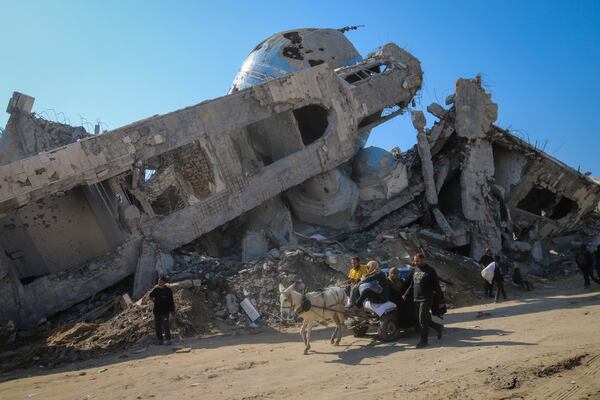 A family rides in a horse-drawn cart past a destroyed mosque in Beit Lahia, northern Gaza Strip, Wednesday, Jan. 29, 2025, after Israel began allowing hundreds of thousands of Palestinians to return to the heavily damaged area last Monday.(AP Photo/Jehaid Alshrafi)