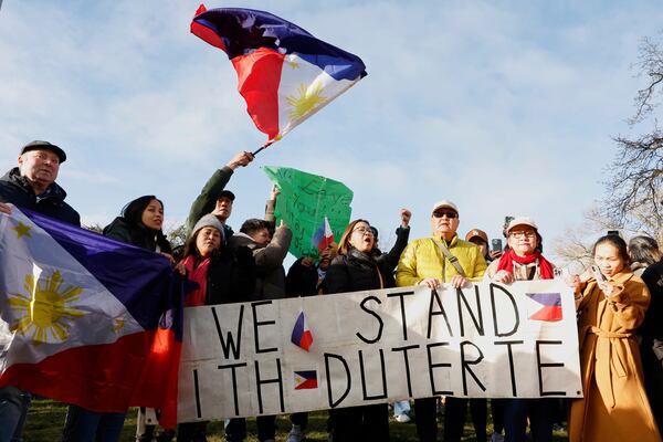 Supporters of former Philippine President Rodrigo Duterte wave a flag and banner during a demonstration outside the International Criminal Court detention center near The Hague in Scheveningen, Netherlands, Wednesday, March 12, 2025. (AP Photo/Omar Havana)