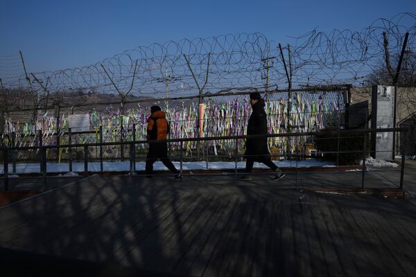 Visitors walk near a wire fence decorated with ribbons written with messages wishing for the reunification of the two Koreas at the Imjingak Pavilion in Paju, South Korea, Wednesday, Jan. 29, 2025. (AP Photo/Lee Jin-man)