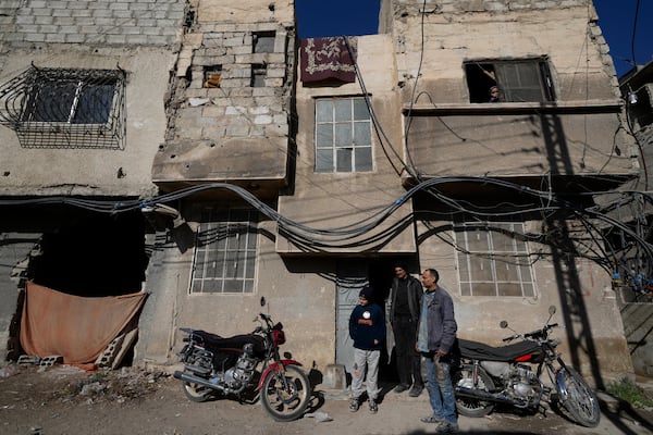 Hussein Arbeeni, 41, right, stands with his brother Hassan Arbeeni, 42, centre, outside their house at an alley that was hit by the sarin struck during a 2013 chemical weapons attack that was blamed on then President Bashar Assad's forces, in Zamalka neighbourhood, on the outskirts of Damascus, Syria, Wednesday, Dec. 25, 2024. (AP Photo/Hussein Malla)