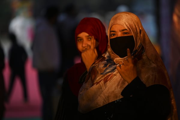 Women show their index fingers marked with indelible ink after casting their votes for Delhi state election at a polling booth in New Delhi, India, Wednesday, Feb. 5, 2025. (AP Photo)