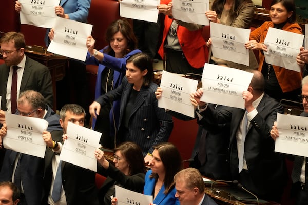 Opposition members of parliament display placards in Italian reading "Meloni where are you?", during a debate in the Italian lower Chamber in Rome, Wednesday, Feb. 5, 2025, over the controversial repatriation, last week, of a Libyan warlord, Ossama Anjiem, also known as Ossama al-Masri, wanted by the International Criminal Court in the Hague, and who had been arrested in Turin, northern Italy. (AP Photo/Gregorio Borgia)