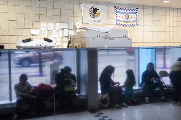 FILE - Immigrants from Venezuela are reflected in a marble wall while taking shelter at the Chicago Police Department's 16th District station on May 1, 2023. (AP Photo/Charles Rex Arbogast, FIle)