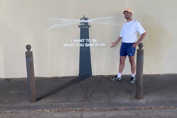 A man poses by an artwork by street artist Banksy, Friday, May 30, 2025 in Marseille, southern France. (AP Photo/Bishr Eltoni)
