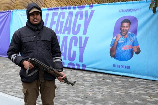 A police officer stands guard next to a banner showing the portraits of India's captain Rohit Sharma outside the Gadafi Stadium, in Lahore, Pakistan, Thursday, Feb. 20, 2025. (AP Photo/K.M Chaudary)