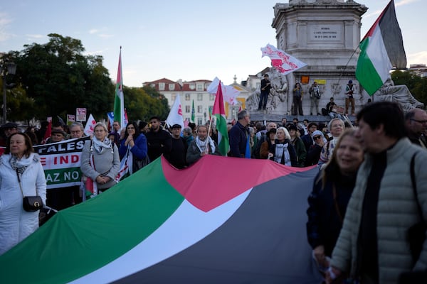 People hold a Palestinian flag during a demonstration for peace and in support for Palestinians, in Lisbon, Saturday, Jan. 18, 2025. (AP Photo/Armando Franca)