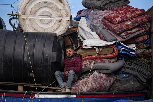 A displaced child sits on a truck loaded with belongings near a roadblock on Salah al-Din Street, as he waits to return to his family home in the northern part of the Gaza Strip, Sunday, Jan. 26, 2025, days after the ceasefire deal between Israel and Hamas came into effect. (AP Photo/Abdel Kareem Hana)