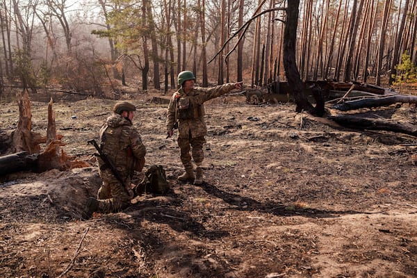 Andrii Serhieiev, right, a soldier with Ukraine's 53rd Brigade who lost a leg in combat, and another soldier install explosives near the front line in Ukraine's Donetsk region on Feb. 13, 2025. (AP Photo/Evgeniy Maloletka)