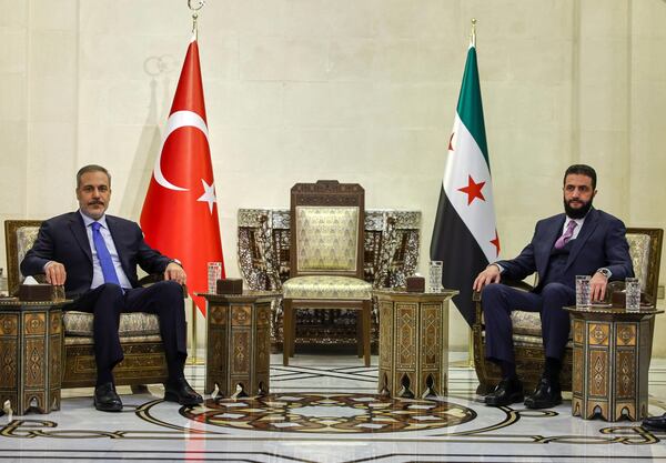 In this handout photo released by the Turkish Foreign Ministry press service, Turkish Foreign Minister Hakan Fidan, left, sits with Syria's interim president Ahmad Al-Sharaa, during their meeting in Damascus, Syria, Thursday, March 13, 2025. (Turkish Foreign Ministry press service via AP)