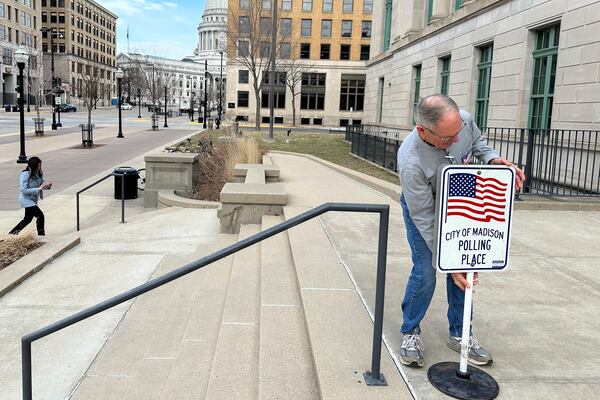 Volunteer Wade DallaGrana puts out a sign ahead of the start of early voting in the Wisconsin Supreme Court race on Tuesday, March 18, 2025, in Madison, Wisconsin. (AP Photo/Scott Bauer)