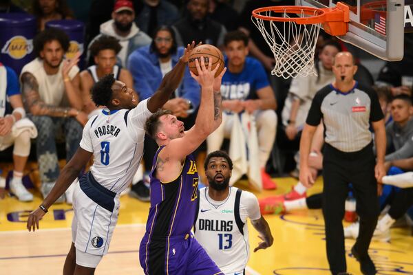 Dallas Mavericks forward Olivier-Maxence Prosper, left, blocks a shot by Los Angeles Lakers guard Luka Doncic during the second half of an NBA basketball game Tuesday, Feb. 25, 2025, in Los Angeles. (AP Photo/Kyusung Gong)