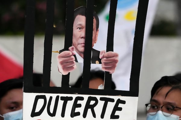 Protesters hold an illustration of former President Rodrigo Duterte behind bars as they call for justice to victims of the war on drugs during his administration in Quezon city, Philippines on Friday, March 14, 2025. (AP Photo/Aaron Favila)