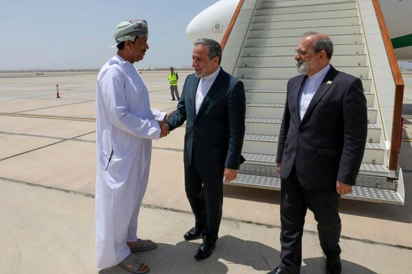 In this photo released by the Iranian Foreign Ministry, Iranian Foreign Minister Abbas Araghchi, center, is welcomed by an unidentified Omani official upon his arrival at Muscat, Oman, for negotiations with U.S. Mideast envoy Steve Witkoff, as Iranian Ambassador to Oman Mousa Farhang stands at right, Sunday, May 11, 2025. (Iranian Foreign Ministry via AP)