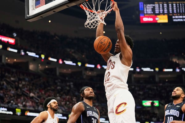 Cleveland Cavaliers forward De'Andre Hunter (12) dunks between Orlando Magic center Wendell Carter Jr. (34) and guard Cory Joseph (10) in the first half of an NBA basketball game Sunday, March 16, 2025, in Cleveland. (AP Photo/Sue Ogrocki)