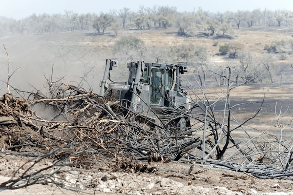 A bulldozer moves charred branches while looking for hotspots in the Crabapple Fire along North State Highway 16 near Fredericksburg, Texas, Monday, March 17, 2025. (Josie Norris/The San Antonio Express-News via AP)