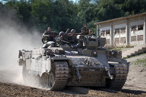 Israeli soldiers wave to the camera from an APC as they cross from the Gaza Strip into Israel, Saturday, Jan. 18, 2025. (AP Photo/Tsafrir Abayov)