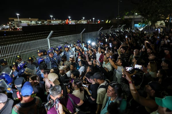 Supporters of former President Rodrigo Duterte rush to the fence of the Villamor Air Base in Manila, Philippines, Wednesday March 11, 2025, upon learning that the plane taking the ex-president to The Hague has left the airport.(AP Photo/Gerard Carreon)