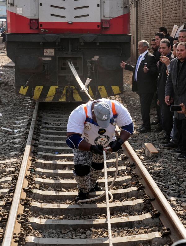 Egyptian wrestler Ashraf Mahrous, better known as Kabonga, pulls a train for nearly 10 meters, 33 feet, at Ramses Station in Cairo, Egypt, as he is watched by Guinness World Record observers, Thursday, March 13, 2025. (AP Photo/Amr Nabil)