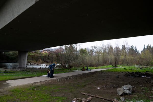 FILE - A homeless person adjusts the jacket after receiving it from another under Redwood Highway near Baker Park, March 22, 2024, in Grants Pass, Ore. (AP Photo/Jenny Kane, File)