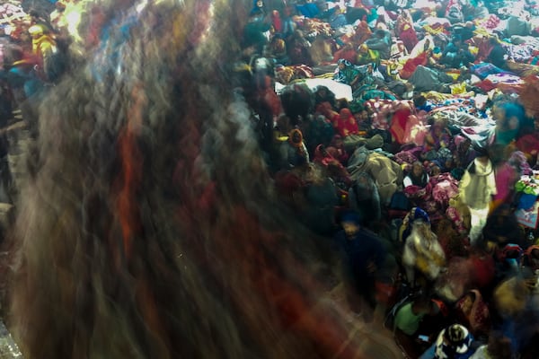 Hindu devotees rest by the banks of the Sangam, the confluence of the Ganges, the Yamuna and the mythical Saraswati rivers, as others move past them in the early hours of 'Mauni Amavasya' or new moon day during the Maha Kumbh festival, in Prayagraj, Uttar Pradesh, India, Wednesday, Jan. 29, 2025. (AP Photo/Rajesh Kumar Singh)