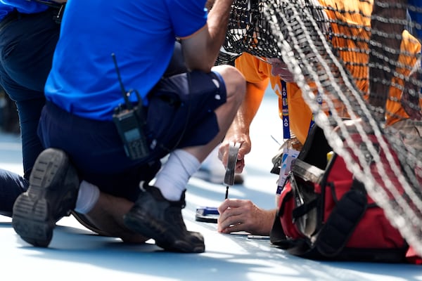 Staff work on repairing the net during the fourth round match between Jannik Sinner of Italy and Holger Rune of Denmark at the Australian Open tennis championship in Melbourne, Australia, Monday, Jan. 20, 2025. (AP Photo/Asanka Brendon Ratnayake)