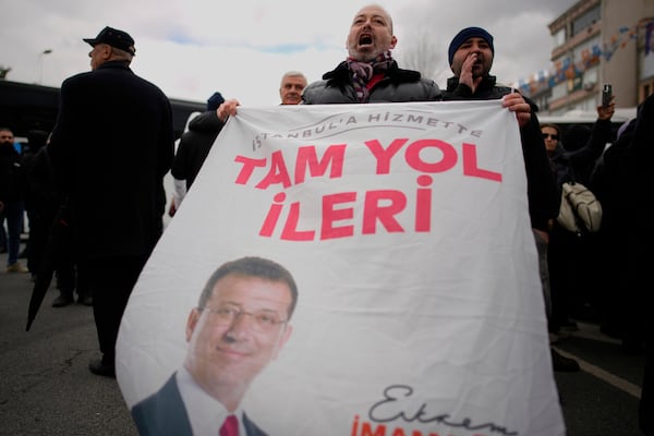 People chant slogans, one holding a banner featuring a photo of Istanbul Mayor Ekrem Imamoglu, while protesting his arrest in Istanbul, Turkey, Wednesday, March 19, 2025. (AP Photo/Emrah Gurel)