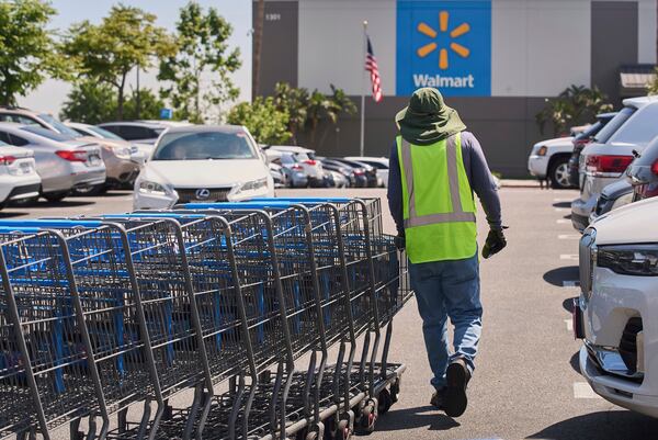 FILE - Empty shopping carts are collected from the parking lot at Walmart store in Burbank, Calif., on Thursday, April 10, 2025. (AP Photo/Damian Dovarganes, File)