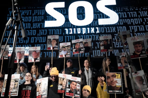 Yael Alexander, center right in grey scarf, holds a poster of her son, Edan, who was taken hostage by Hamas militants on Oct. 7, 2023, on stage with family, during a weekly rally for families of hostages held in the Gaza Strip and their supporters, in Tel Aviv, Israel, Saturday, Feb. 22, 2025. (AP Photo/Maya Alleruzzo)