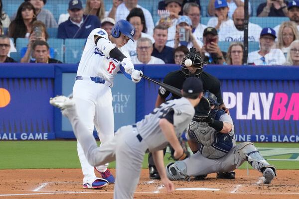 Los Angeles Dodgers' Shohei Ohtani, left, hits a solo home run as New York Yankees starting pitcher Max Fried, center, and catcher Austin Wells watch during the first inning of a baseball game Friday, May 30, 2025, in Los Angeles. (AP Photo/Mark J. Terrill)