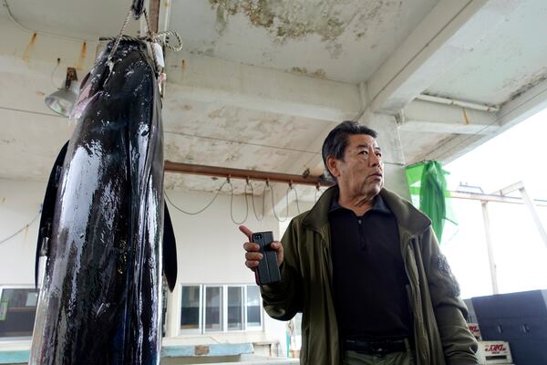 Shigenori Takenishi, the head of the fisheries cooperative, stands beside a hanging swordfish during an interview on Yonaguni, a tiny island on Japan’s western frontier, Friday, Feb. 14, 2025. (AP Photo/Mari Yamaguchi)